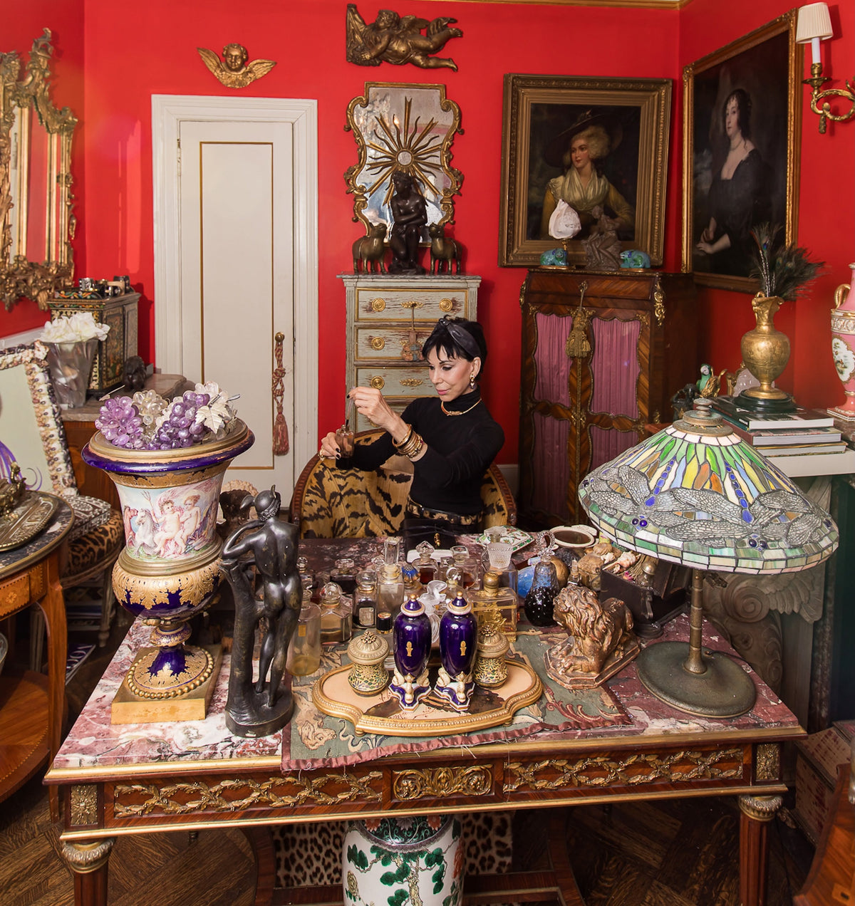 At the center of the Collesta universe sits Cynthia at her historic Millet et Fils desk, clothed in her signature black ensemble accented by a Cartier panther necklace, Marina B earrings, and a vintage circa 1960 leopard belt. Surrounding her are the