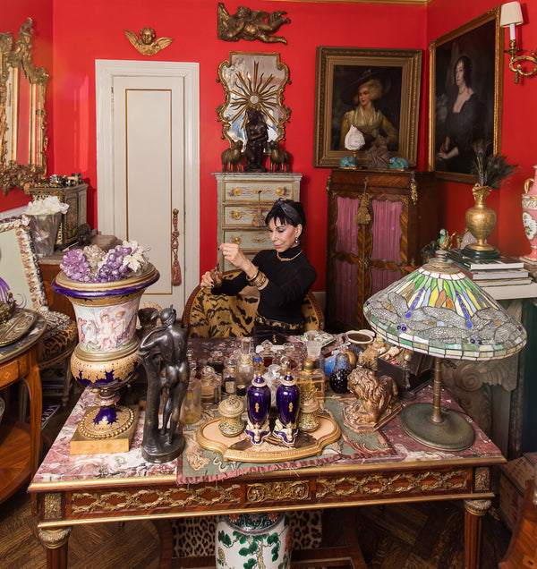At the center of the Collesta universe sits Cynthia at her historic Millet et Fils desk, clothed in her signature black ensemble accented by a Cartier panther necklace, Marina B earrings, and a vintage circa 1960 leopard belt. Surrounding her are the