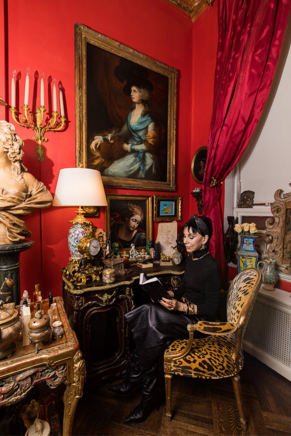 Cynthia studies from her personal alchemy  book, a  hand written archive of  her  fragrance compositions and skin care formulas.    The Regency period chair, gilt and upholstered in Scalamandré Leopardo, introduces  dialogue between fashion and furni